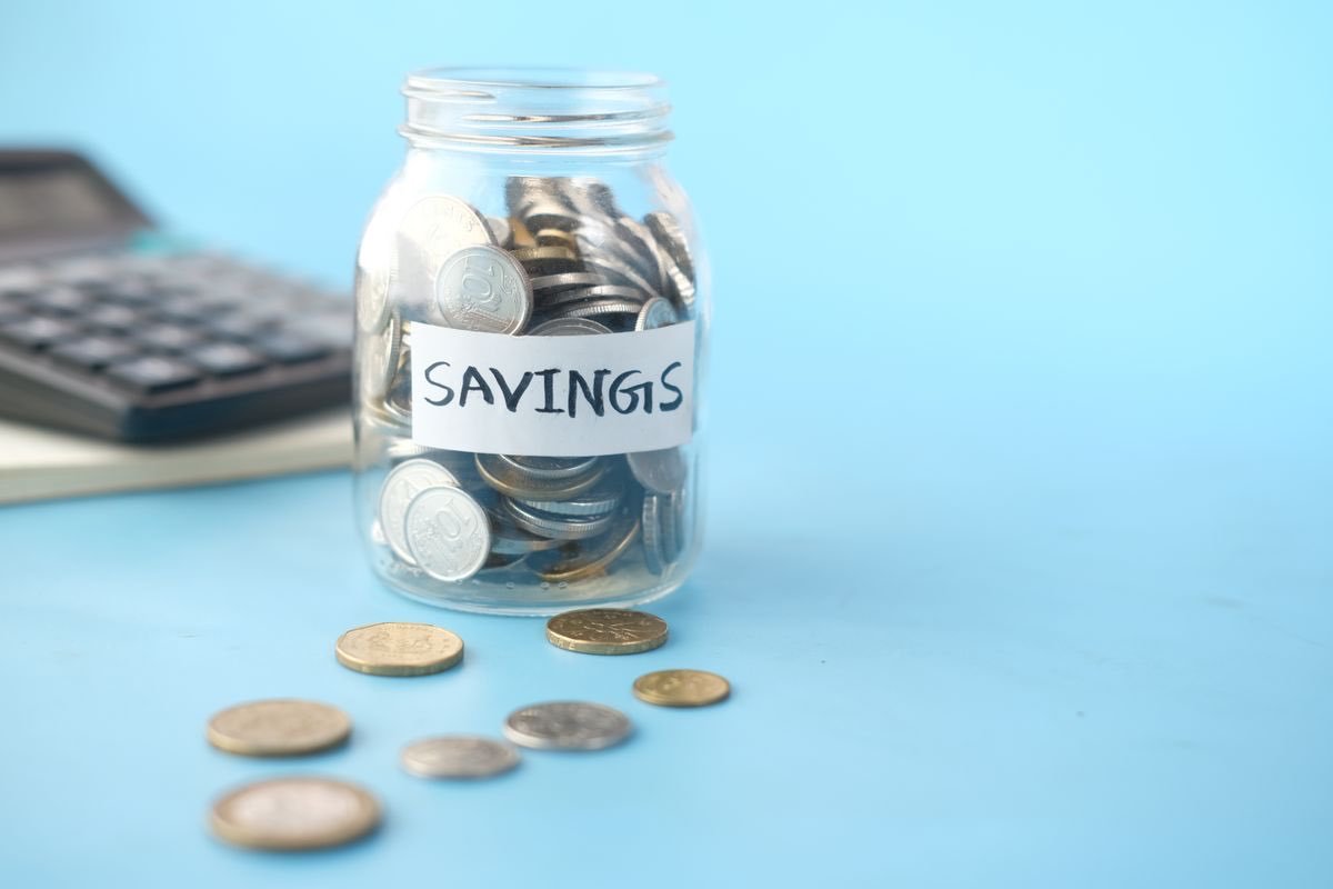 A glass jar of coins beside a calculator, illustrating budgeting